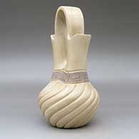 A beige wedding vase with a swirl melon-carved body and a band of black on beige scrolls geometric design around the neck, click or tap to see a larger version