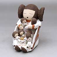 A sitting grandmother storyteller wearing a manta and holding six children with a bowl of food
 by Chris Teller of Isleta