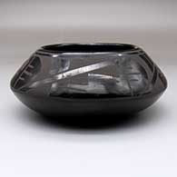 A black-on-black bowl decorated with a four-panel geometric design above the shoulder
 by Minnie Vigil of Santa Clara