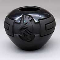A black-on-black bowl carved with a two-panel kokopelli and scrolls geometric design with inlaid blue stones for the eyes
 by Harrison Begay Jr of Santa Clara