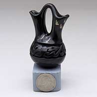 A miniature black wedding vase with a carved avanyu design around the shoulder and a sgraffito geometric design on one spout
 by Nancy Youngblood of Santa Clara