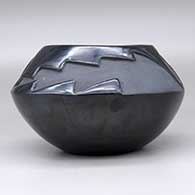A black bowl carved above the shoulder with a two-panel geometric design, click or tap to see a larger version