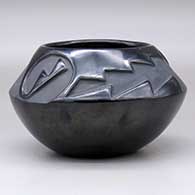A black bowl carved above the shoulder with a two-panel geometric design, click or tap to see a larger version