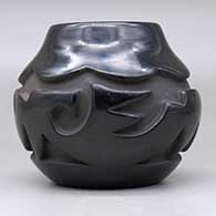 A black jar with an avanyu and geometric design carved around the body, click or tap to see a larger version