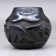 A black jar with an avanyu and geometric design carved around the body, click or tap to see a larger version