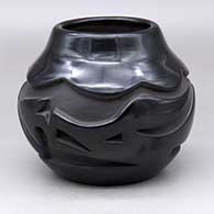 A black jar with an avanyu and geometric design carved around the body
 by Madeline Naranjo of Santa Clara