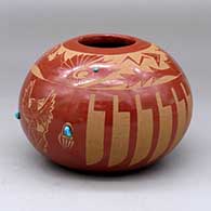 A red bowl decorated with a sgraffito feather, avanyu, dancer,bear paw and geometric design with five inlaid stones
 by Laura Tafoya of Santa Clara