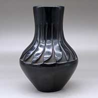 A black vase carved above the shoulder with a ring of feathers design, click or tap to see a larger version