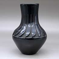 A black vase carved above the shoulder with a ring of feathers design, click or tap to see a larger version