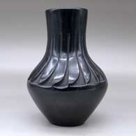 A black vase carved above the shoulder with a ring of feathers design, click or tap to see a larger version