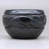 A black bowl with a carved avanyu design around the body, click or tap to see a larger version