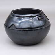 A black bowl carved with a stylized avanyu design above the shoulder
 by Mida Tafoya of Santa Clara