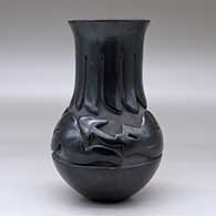 A tall-neck black jar carved with an avanyu design above the shoulder and a ring of feathers design around the neck, click or tap to see a larger version