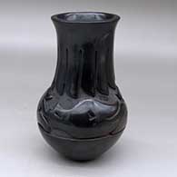 A tall-neck black jar carved with an avanyu design above the shoulder and a ring of feathers design around the neck
 by Mida Tafoya of Santa Clara