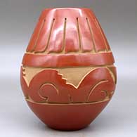 A red jar carved around the body with an avanyu and feather design, click or tap to see a larger version