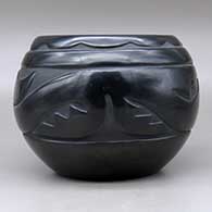 A black bowl carved around the body with an avanyu and geometric design, click or tap to see a larger version