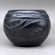 A black bowl carved around the body with an avanyu and geometric design, click or tap to see a larger version