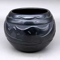 A black bowl carved around the body with an avanyu and geometric design
 by Mary Singer of Santa Clara
