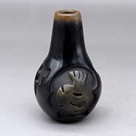 A black jar with a tall neck, sienna rim and spots, and decorated around the shoulder with a four panel carved kokopelli and kiva step design
 by Anita L Suazo of Santa Clara