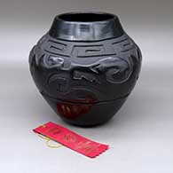 A black on black jar carved with an avanyu, scroll and geometric design, Second Prize ribbon from the Gallup InterTribal Ceremonial
 by Sharon Naranjo Garcia of Santa Clara