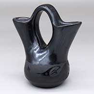 A small black-on-black wedding vase decorated with an avanyu design around the body
 by Marvin and Frances Martinez of San Ildefonso