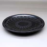 A black on black plate decorated with a ring of feathers and cloud formation geometric design, click or tap to see a larger version