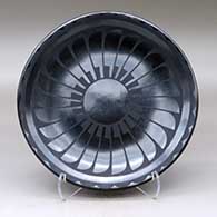 A black on black plate decorated with a ring of feathers and cloud formation geometric design
 by Carlos Sunrise Dunlap of San Ildefonso