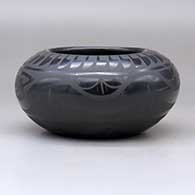 A black on black bowl decorated around the body with a plumed avanyu, ring of feathers, cloud formation and geometric design, click or tap to see a larger version