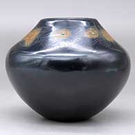 A black jar with sienna spots and inlaid stones, decorated above the shoulder with a sgraffito avanyu, feather, fineline and geometric design, click or tap to see a larger version