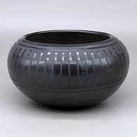 A black on black bowl decorated with a band of feathers design around the shoulder
 by Blue Corn of San Ildefonso