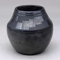 A black on black jar decorated with a four panel kiva step geometric design above the shoulder
 by Tonita Roybal of San Ildefonso