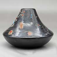 A low shouldered black jar with a sienna rim and spots, inlaid stones and decorated with a sgraffito avanyu, feather, spider, butterfly and geometric design, click or tap to see a larger version