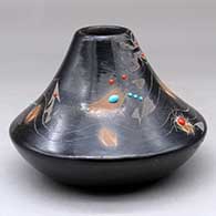 A low shouldered black jar with a sienna rim and spots, inlaid stones and decorated with a sgraffito avanyu, feather, spider, butterfly and geometric design
 by Barbara Gonzales of San Ildefonso