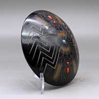 A black seed pot with sienna spots, inlaid stones and a sgraffito spider, web and geometric design, click or tap to see a larger version