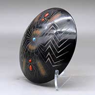 A black seed pot with sienna spots, inlaid stones and a sgraffito spider, web and geometric design, click or tap to see a larger version