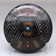 A black seed pot with sienna spots, inlaid stones and a sgraffito spider, web and geometric design
 by Barbara Gonzales of San Ildefonso