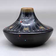 A low shouldered black jar with a sienna rim and spots, inlaid stones and decorated with a sgraffito avanyu, feather, spider and geometric design, click or tap to see a larger version