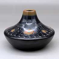 A low shouldered black jar with a sienna rim and spots, inlaid stones and decorated with a sgraffito avanyu, feather, spider and geometric design
 by Barbara Gonzales of San Ildefonso