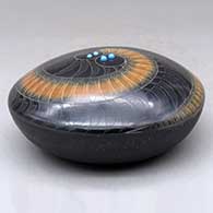 A black seed pot with a black micaceous base and a sienna spiral in a sgraffito feather and geometric design, plus five inlaid stones, click or tap to see a larger version