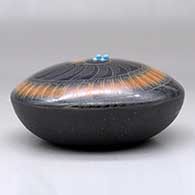 A black seed pot with a black micaceous base and a sienna spiral in a sgraffito feather and geometric design, plus five inlaid stones, click or tap to see a larger version