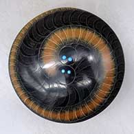 A black seed pot with a black micaceous base and a sienna spiral in a sgraffito feather and geometric design, plus five inlaid stones
 by Barbara Gonzales of San Ildefonso