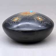 A black seed pot with sienna spots, inlaid stones and a sgraffito spider, spider web and geometric design, click or tap to see a larger version
