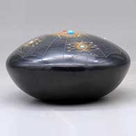 A black seed pot with sienna spots, inlaid stones and a sgraffito spider, spider web and geometric design, click or tap to see a larger version