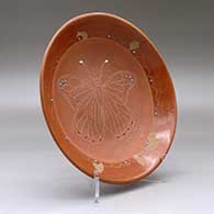 A red and micaceous red shallow bowl decorated with inlaid stones and a sgraffito butterfly and geometric design, click or tap to see a larger version