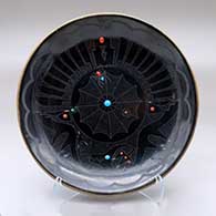 A black plate with inlaid stones and a sgraffito avanyu, feather, spider and geometric design
 by Barbara Gonzales of San Ildefonso