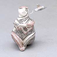 A miniature polychrome matachine figure decorated with a fineline geometric design and with a hummingbird hovering nearby
 by Carla Martinez of Mata Ortiz and Casas Grandes