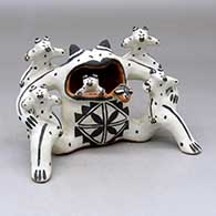 A frog storyteller figure carrying five babies with a fly on its tongue
 by Martha Arquero of Cochiti