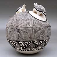 A black-on-white seed pot with two turtle appliques and the whole decorated with a fine line snowflake and geometric design, click or tap to see a larger version