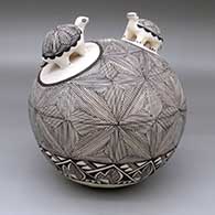A black-on-white seed pot with two turtle appliques and the whole decorated with a fine line snowflake and geometric design
 by Hilda Antonio of Acoma