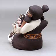 A sitting grandmother storyteller figure with three children, a pot and a turtle, click or tap to see a larger version